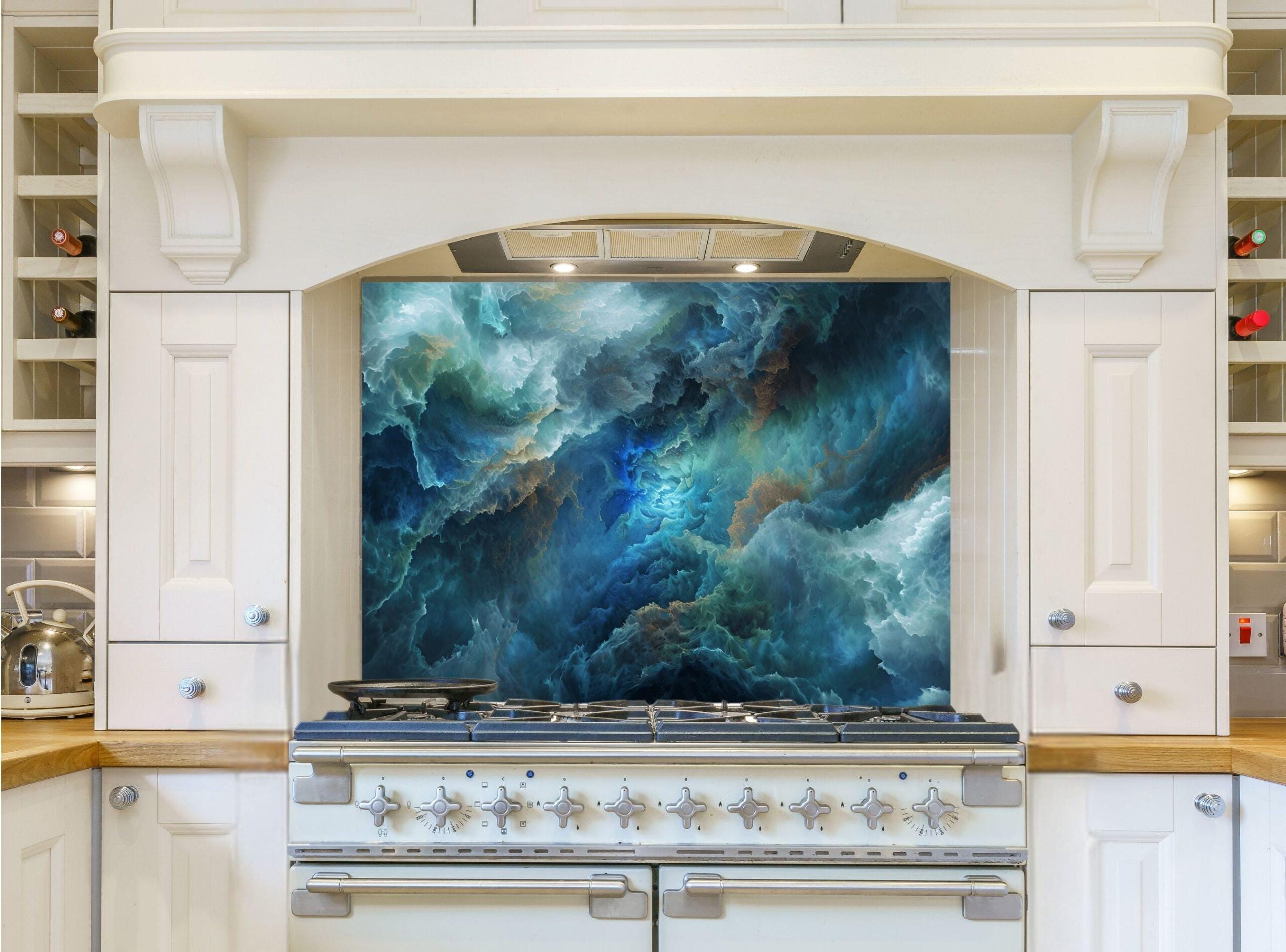 May include: A white kitchen with a stainless steel range hood and a blue and green abstract art glass backsplash. The range hood has a light fixture and the range has six burners and two ovens.
