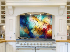 May include: A white kitchen range with a colorful abstract backsplash. The backsplash is made of glass tiles in shades of blue, green, yellow, orange, and red. The range has a black burner grate and a white control panel with silver knobs.