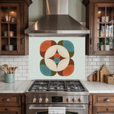 May include: A kitchen backsplash with a retro-style geometric design. The design features a central white circle with a starburst pattern, surrounded by orange, teal, and brown rounded shapes. The backsplash is mounted above a stainless steel gas range.