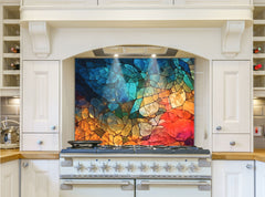 May include: A white kitchen range with a colorful stained glass backsplash. The backsplash has a mosaic design of blue, green, yellow, orange, and red. The range has a black cooktop with eight silver knobs and a silver oven door.