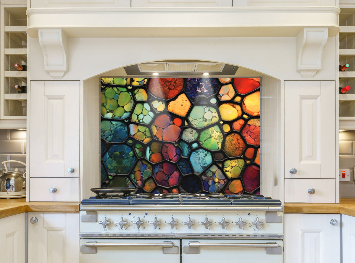 May include: A colorful stained glass style kitchen backsplash with a variety of colors including red, orange, yellow, green, blue, and purple. The backsplash is installed above a white stove with silver knobs.