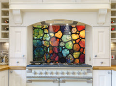 May include: A colorful stained glass style kitchen backsplash with a variety of colors including red, orange, yellow, green, blue, and purple. The backsplash is installed above a white stove with silver knobs.