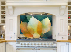 May include: A white kitchen range with a glass backsplash featuring a painting of three large, overlapping leaves in shades of yellow, orange, and green. The leaves are painted in a watercolor style and have a soft, ethereal quality. The backsplash is set against a backdrop of a deep blue-green color.