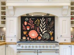 May include: A white kitchen with a black range hood and a floral patterned backsplash. The backsplash features a variety of flowers and leaves in shades of pink, orange, and yellow on a black background. The range hood is above a white range with six burners and a black oven door.