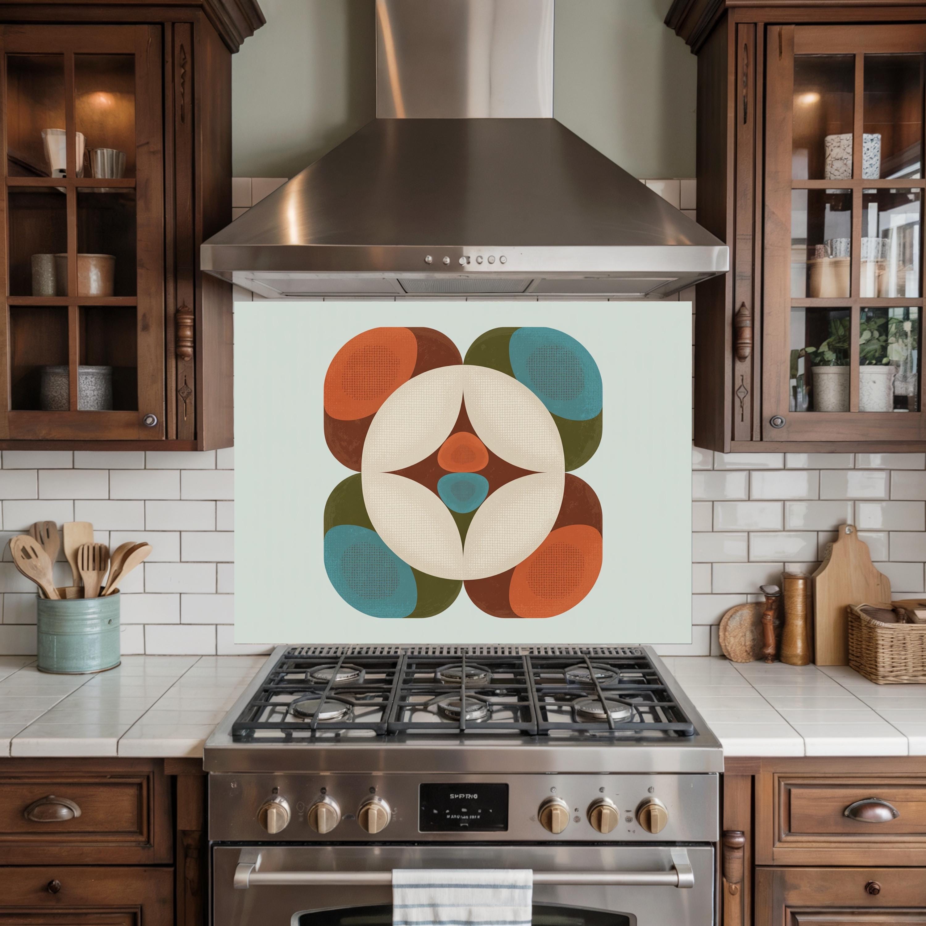 May include: A kitchen backsplash with a retro-style geometric design. The design features a central white circle with a starburst pattern, surrounded by orange, teal, and brown rounded shapes. The backsplash is mounted above a stainless steel gas range.